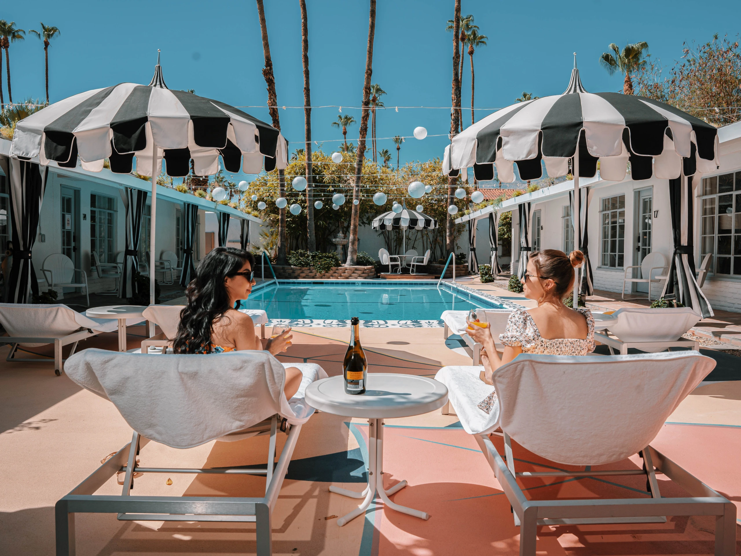 Two women sit in lounge chairs around the pool at the Spirit of Sofia boutique hotel in Palm Springs, California
