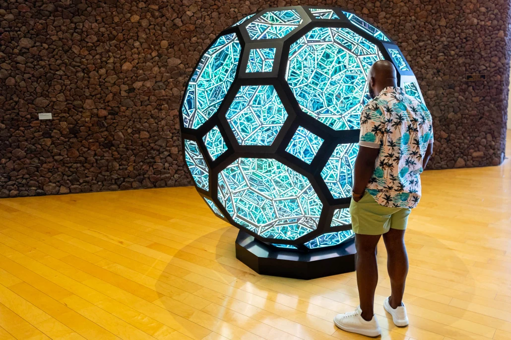A man looks at a blue spherical sculpture at the Palm Springs Art Museum