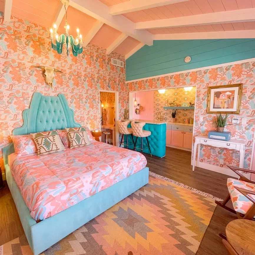 The Yee-Haw Cowgirl suite at Trixie Motel in Palm Springs has a blue and pink motif with a custom bed frame and cowboy-themed wallpaper