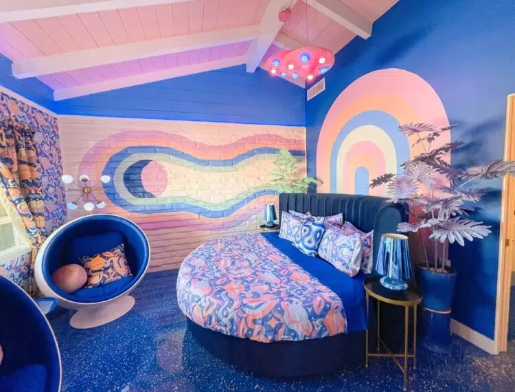 The Atomic Bombshell room at the Trixie Motel has a custom space mural on the wall and a UFO-shaped light hanging over the bed