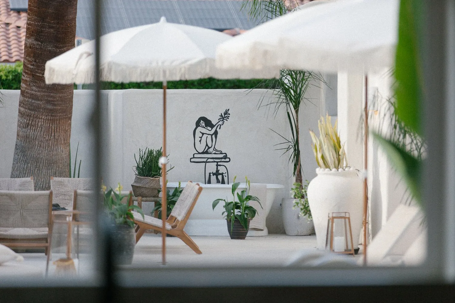 White sun umbrellas shade an outdoor communal space at Yara Hotel in Palm Springs, California