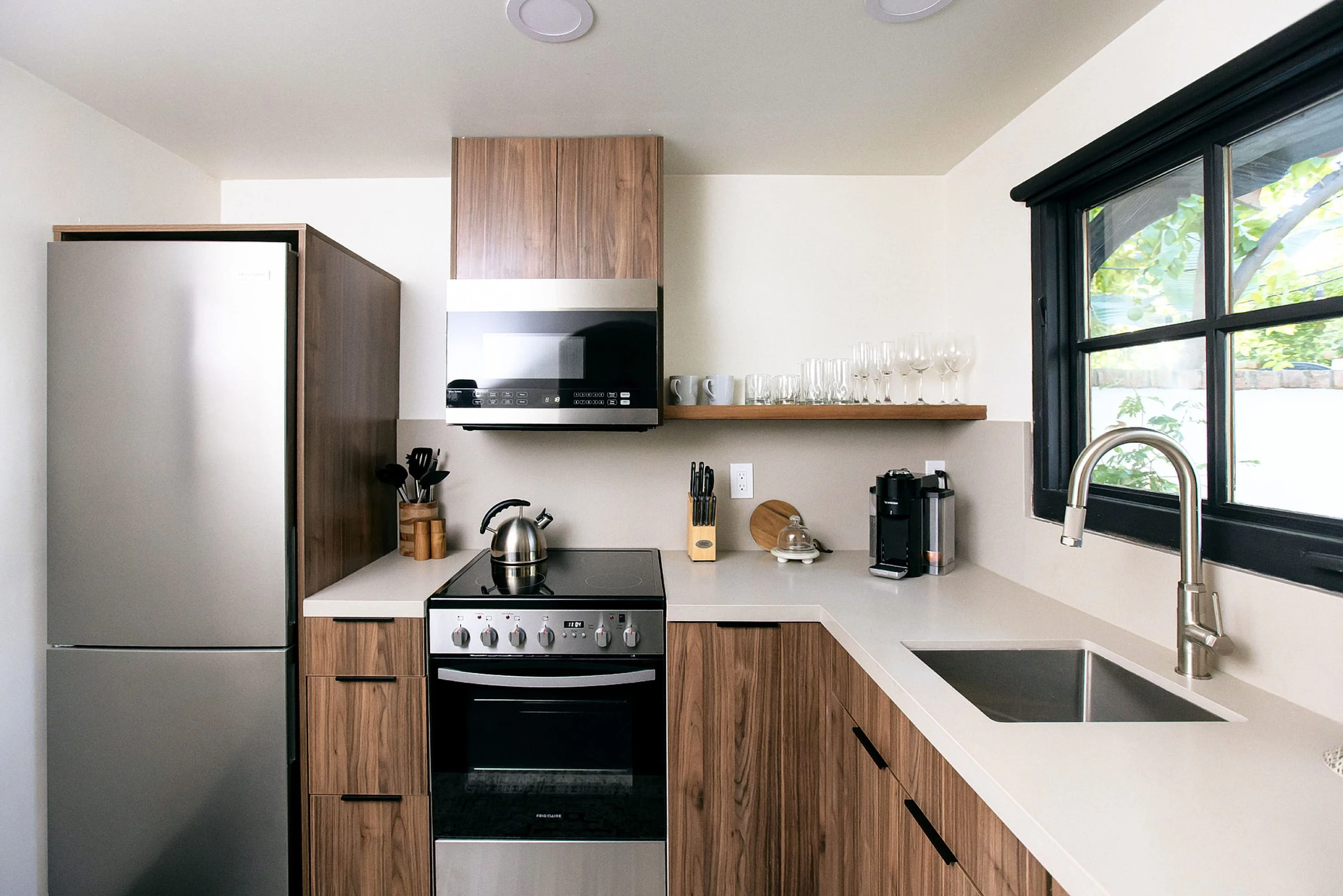 The kitchenette of a villa at The Lucille Palm Springs with a stove and microwave and sink and full refrigerator
