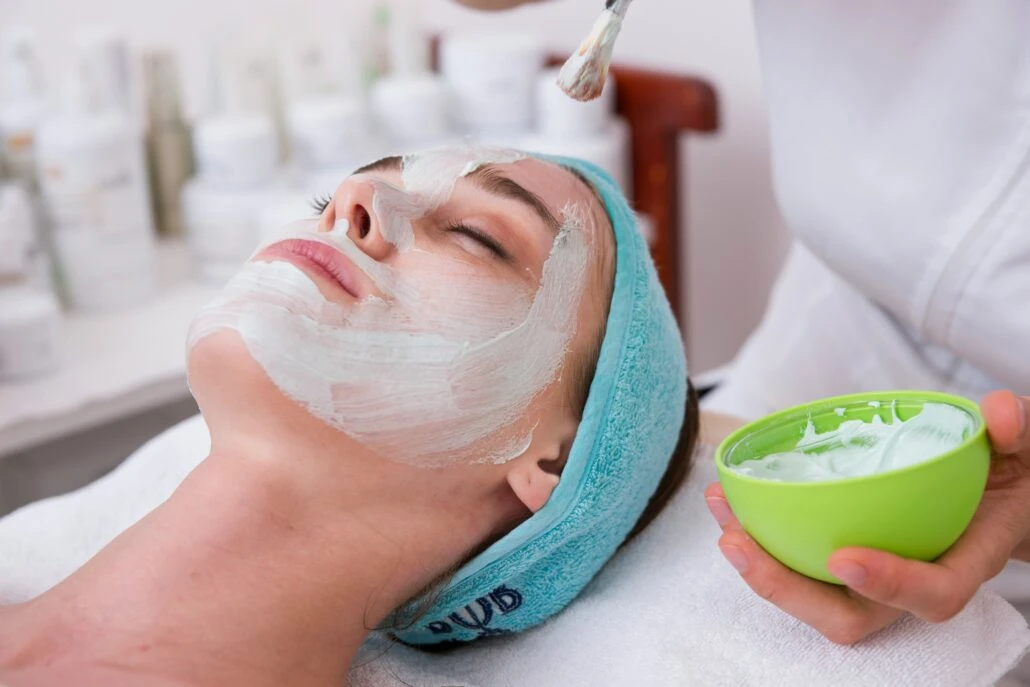 A woman receiving a facial with a mud mask