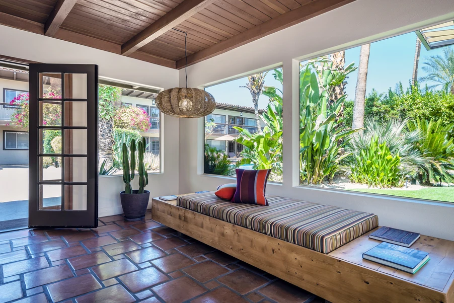 A wooden bench with a striped pillow on top of it in a room at Santiago Resort with dark tiled flooring