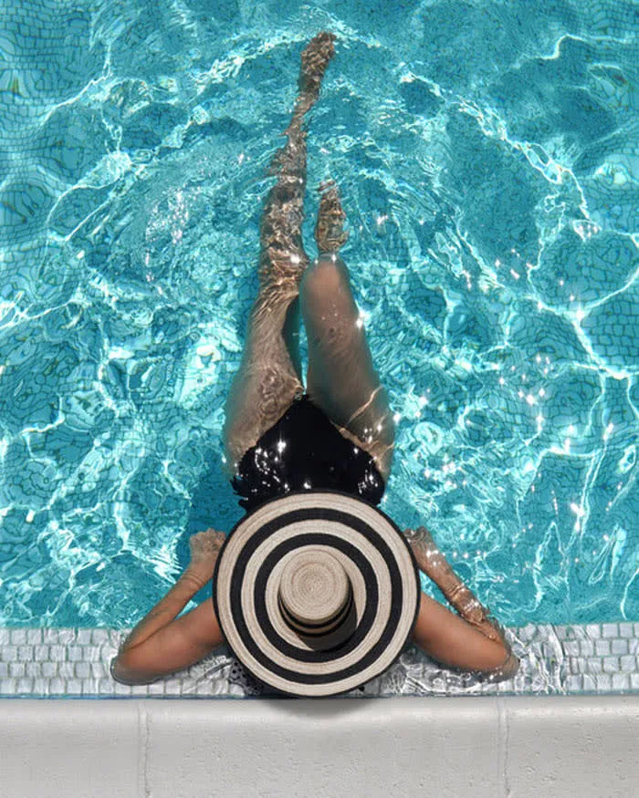 A woman wearing a striped hat reclines in a pool