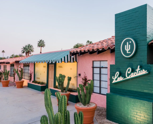 The front entrance to Les Cactus Palm Springs painted green and pink with cacti in pots