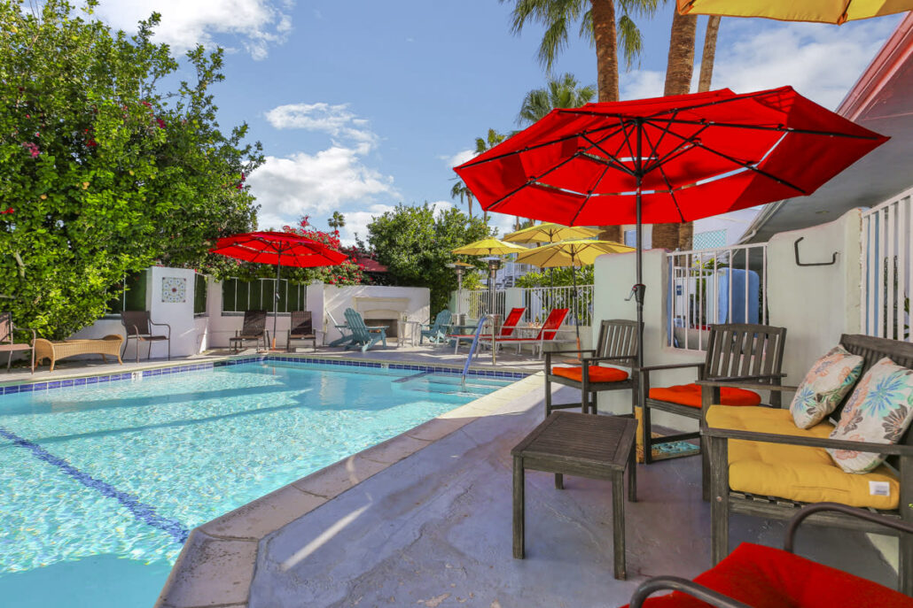 The pool at Inn at Palm Springs surrounded by umbrellas and chairs